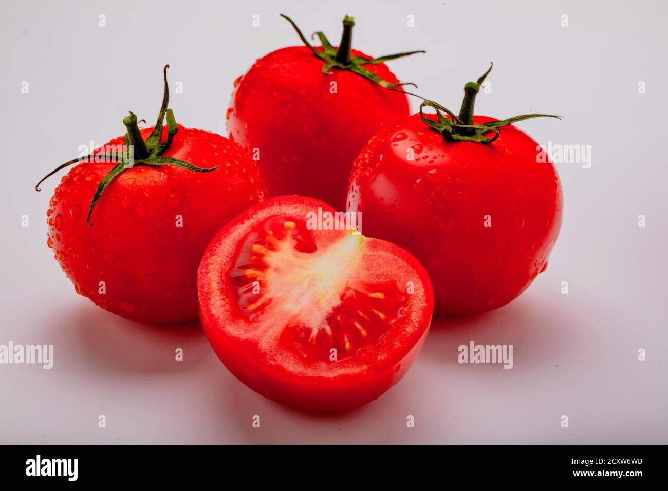 Three wet tomatoes plus one cut open Stock Photo