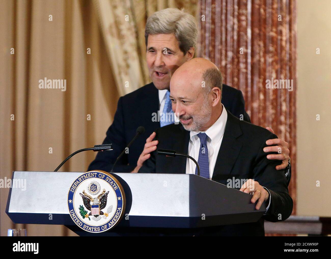 U.S. Secretary of State John Kerry (L) helps Goldman Sachs Chairman and CEO Lloyd Blankfein adjust the podium at the Goldman Sachs 10,000 Women/State Department Entrepreneurship Program at the State Department in Washington, March 9, 2015. REUTERS/Gary Cameron (UNITED STATES) Stock Photo