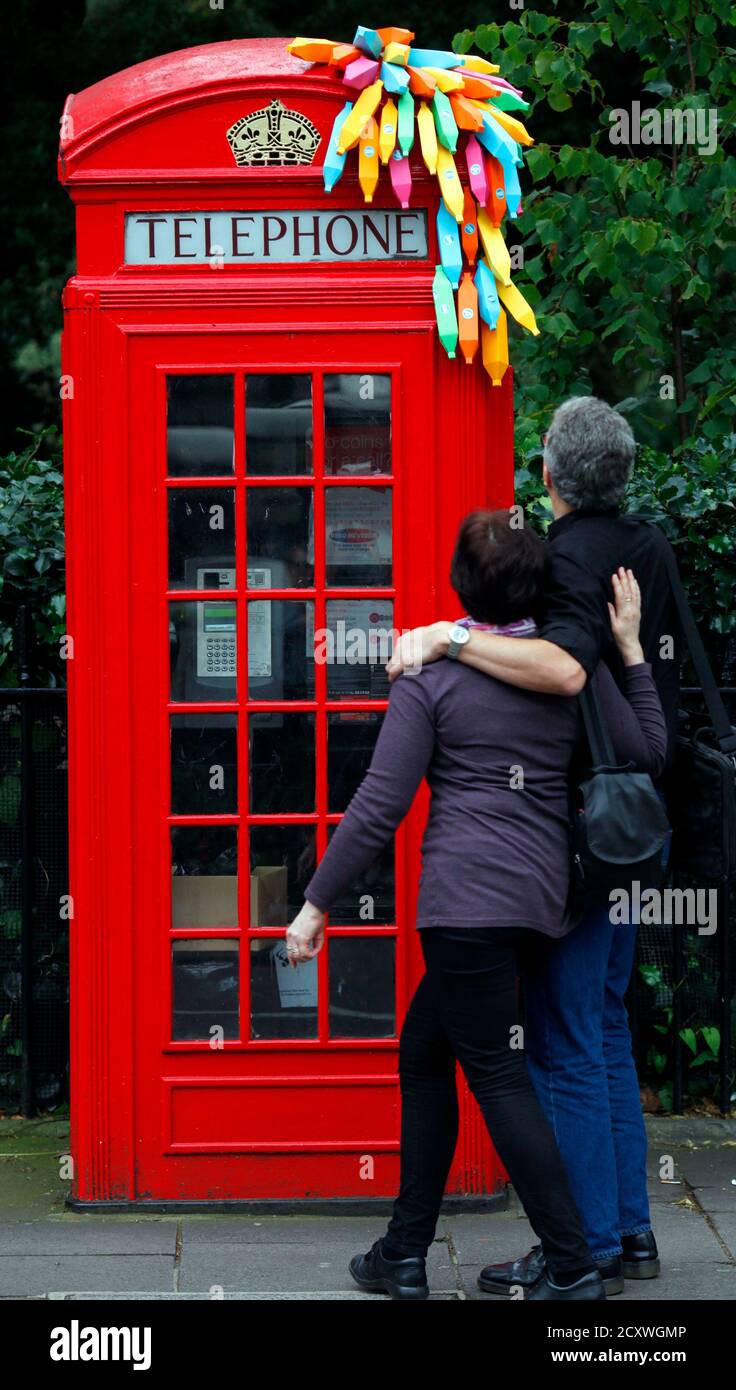 A couple view an installation by Brazilian graphic artist Breno Pineschi, of bananas attached to a public telephone box, as part of as part of the arts campaign 'Rio Occupation London' in South Kensington, London July 19, 2012. Before London hands over the Olympic baton to Rio De Janeiro, 30 of Rio's top artists have 30 days to blast the capital with their city's most vibrant, cutting edge, culture.  REUTERS/Andre Camara  (BRITAIN - Tags: ENTERTAINMENT SOCIETY SPORT OLYMPICS) Stock Photo