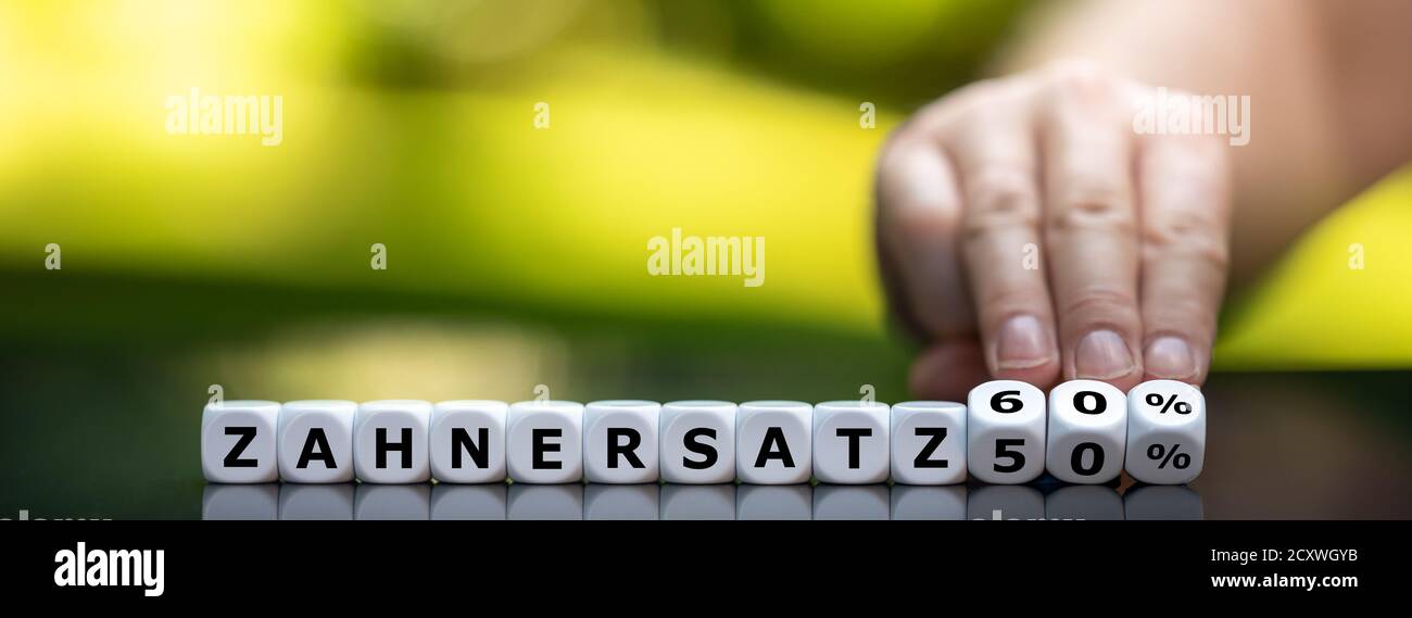 Symbol for the icrease of dental  insureance grants from 50 % to 60 % in Germany. Hand turns dice and changes the German expression 'Zahnersatz 50 %' Stock Photo