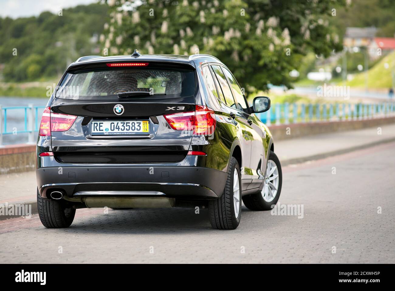 GRODNO, BELARUS - JUNE 2020: BMW X3 II F25 2.0i xDrive selective focus three fourth back view with wheels turned outdoors on sunny road summer city Stock Photo