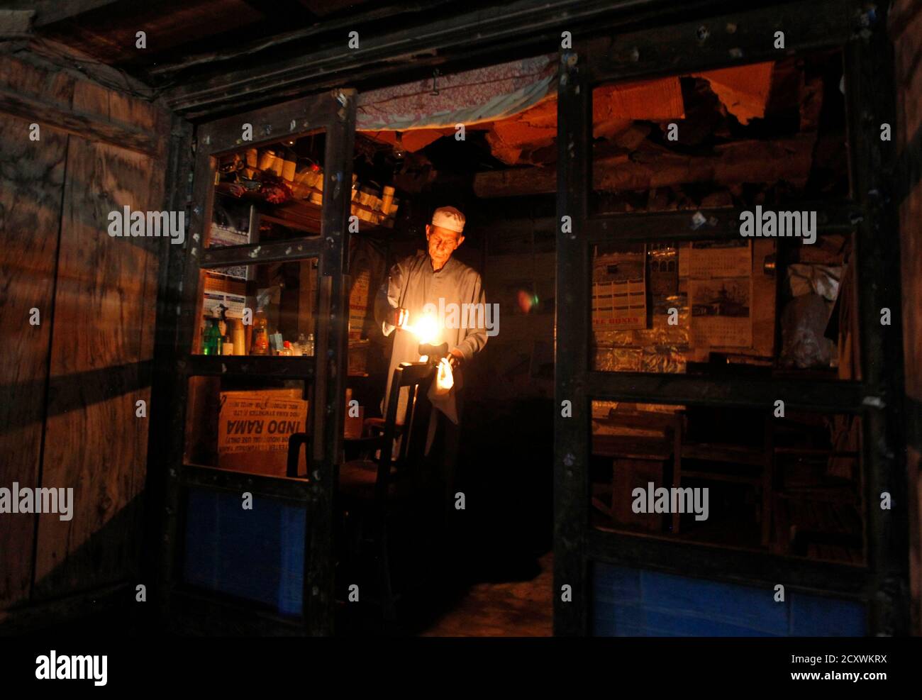 A barber lights candles after a power-cut due to curtailment, at his shop in Srinagar July 3, 2013. India is betting a gas price hike will boost supply and help fix the country's chronic power shortages, but the plan may falter unless the debt-laden industry can pass on higher energy costs to consumers or win government subsidies. Picture taken July 3, 2013. To match story INDIA-POWER/ REUTERS/Danish Ismail (INDIAN-ADMINISTERD KASHMIR - Tags: ENERGY BUSINESS) Stock Photo