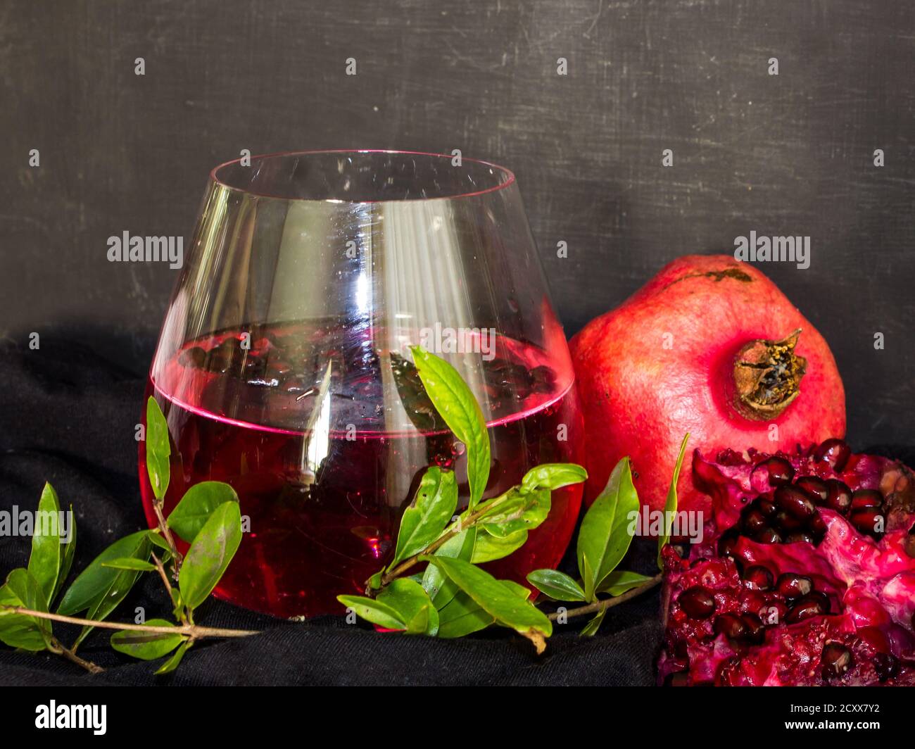 Still life of a red, pomegranate flavored gin and tonic cocktail