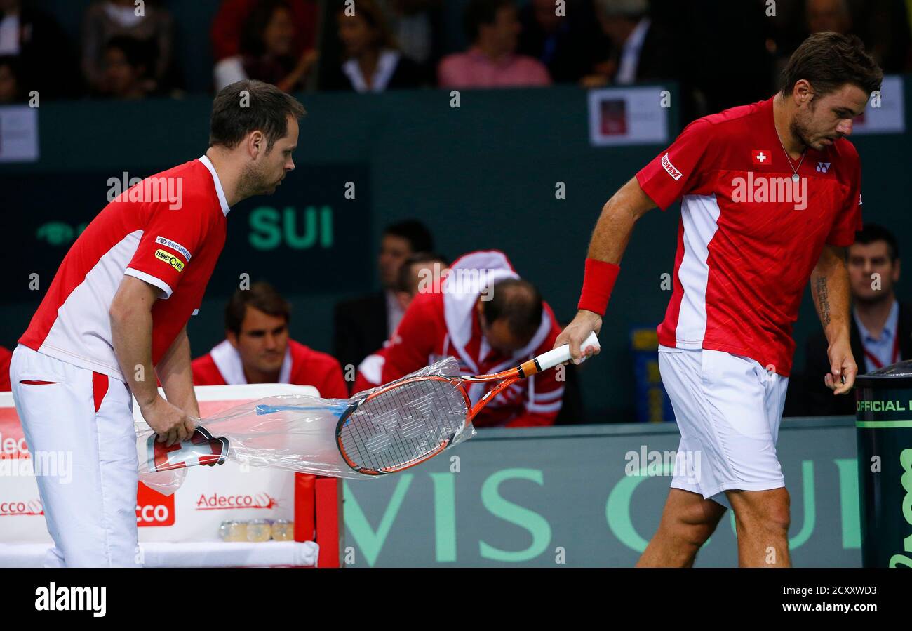 Stanislas Wawrinka of Switzerland takes off a new racket of team captain  Severin Luethi during his Davis Cup quarter-final tennis match against  Andrey Golubev of Kazakhstan in Geneva April 4, 2014. REUTERS/Denis