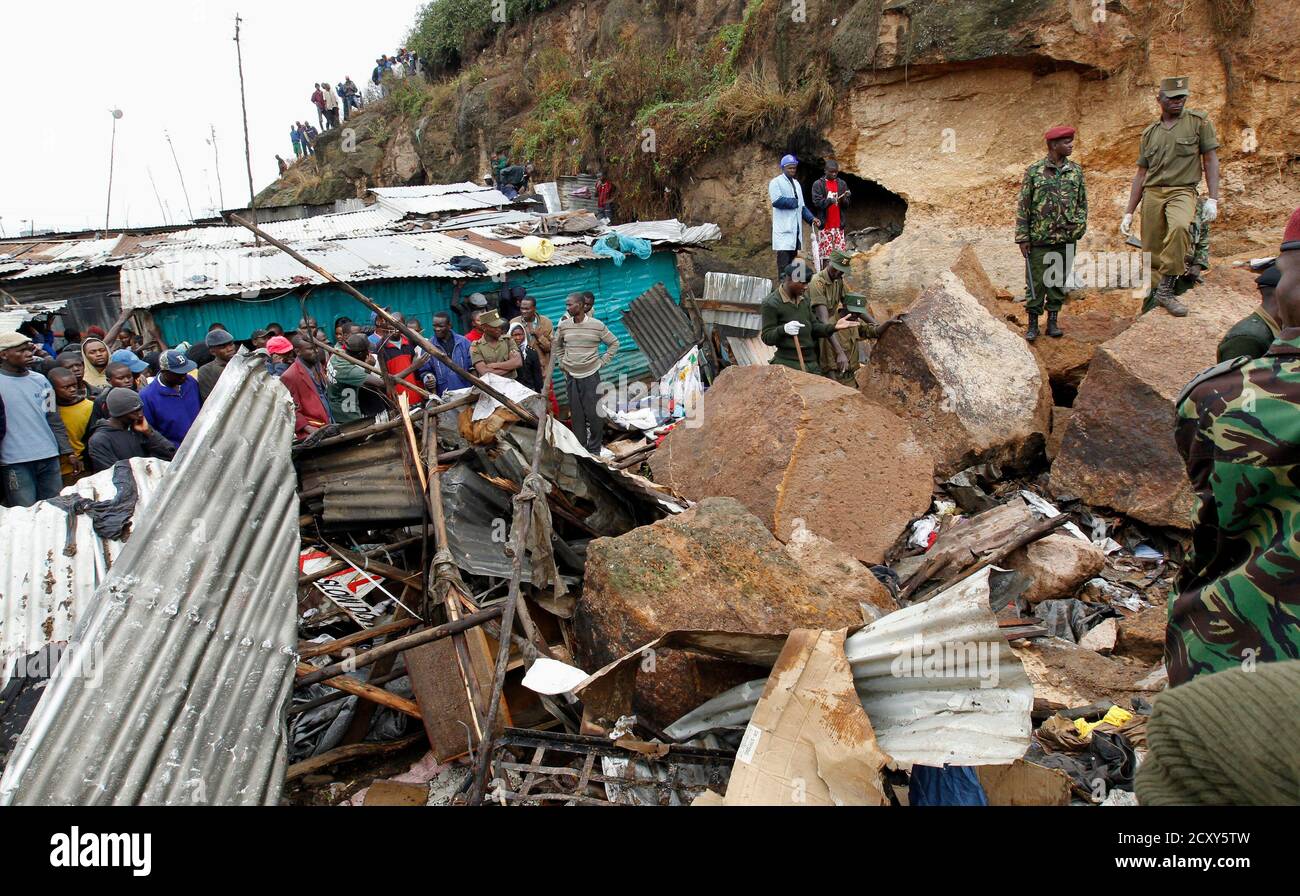 Rescuers stand near the ruins at the Mathare valley slum after boulders, rocks and mud tumbled down a hillside overlooking the slum, smashing into the houses and burying the occupants, in Kenya's capital Nairobi, April 4, 2012. More than four people are feared dead while scores of others are trapped as the heavy rains led to a landslide in one of Kenya's biggest slums crammed with tin and mud shanty houses. Rescue officials said the cramped nature of the slum dwellings were hindering rescue operations. REUTERS/Thomas Mukoya (KENYA - Tags: SOCIETY DISASTER ENVIRONMENT) Stock Photo