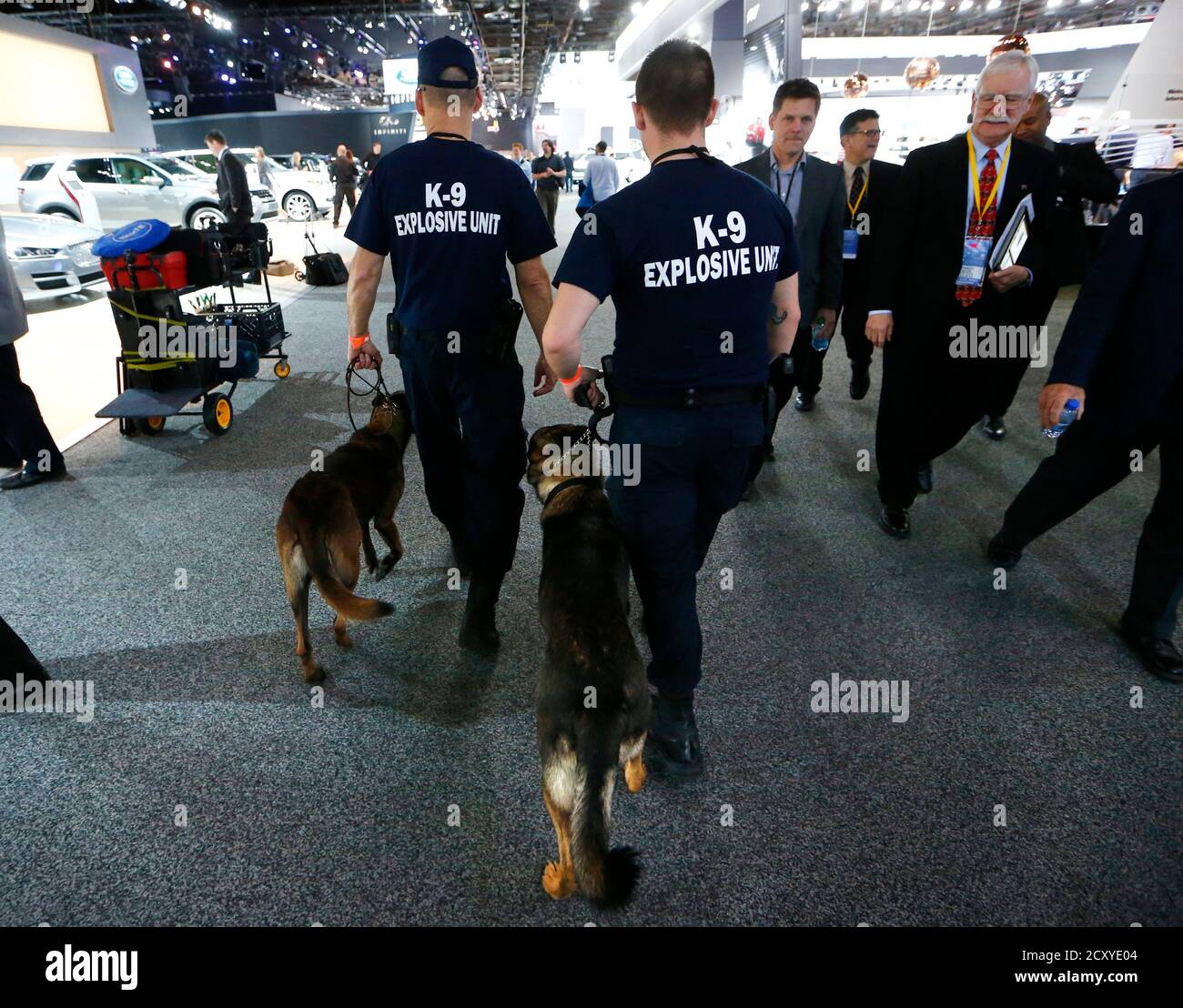 Two police officers guide bomb-sniffing dogs past exhibits during the second press day of the North American International Auto Show in Detroit, Michigan, January 13, 2015.   REUTERS/Mark Blinch (UNITED STATES - Tags: TRANSPORT BUSINESS CRIME LAW) Stock Photo