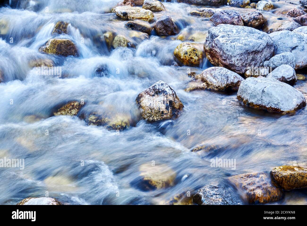 natural background - water flow in a rocky mountain stream is blurred ...