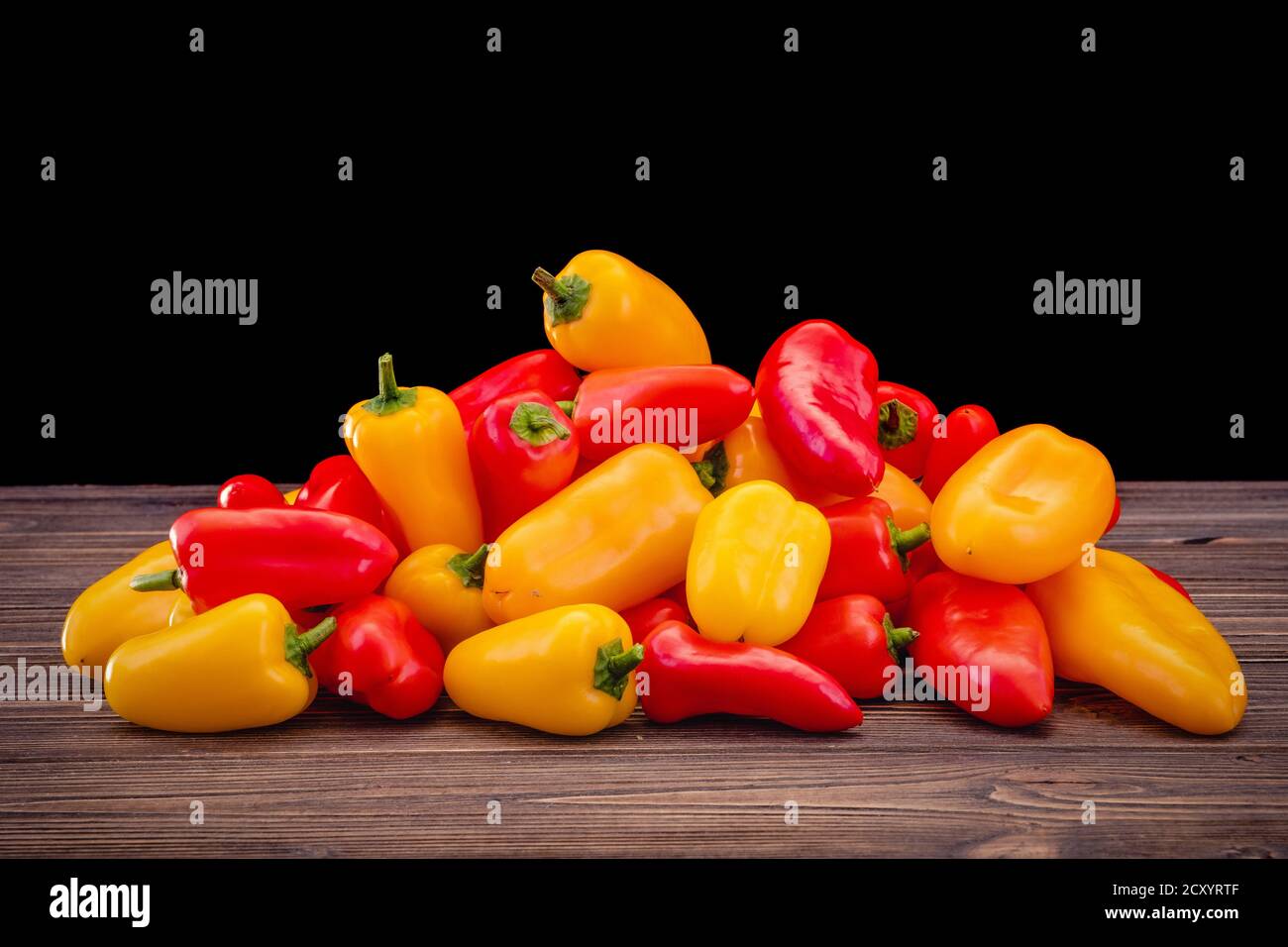 Fresh colored bell peppers on a rustic wooden background. Stock Photo