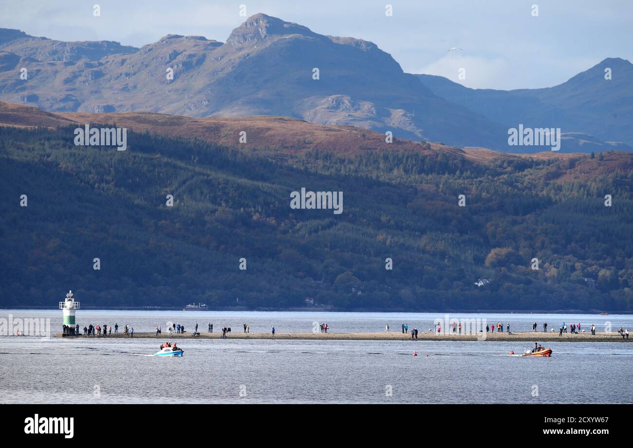 Crowds watch at Rhu Narrows as boats try and move a bottlenose whale from the Gare Loch. Rescuers from British Divers Marine Life Rescue Medics (BDMLR) are using boats in an attempt to herd a pod of northern bottlenose whales out of Loch Long amid concern over the potential impact from Exercise Joint Warrior, a major international military exercise planned for the area, as whales are particularly sensitive to underwater sounds. Stock Photo