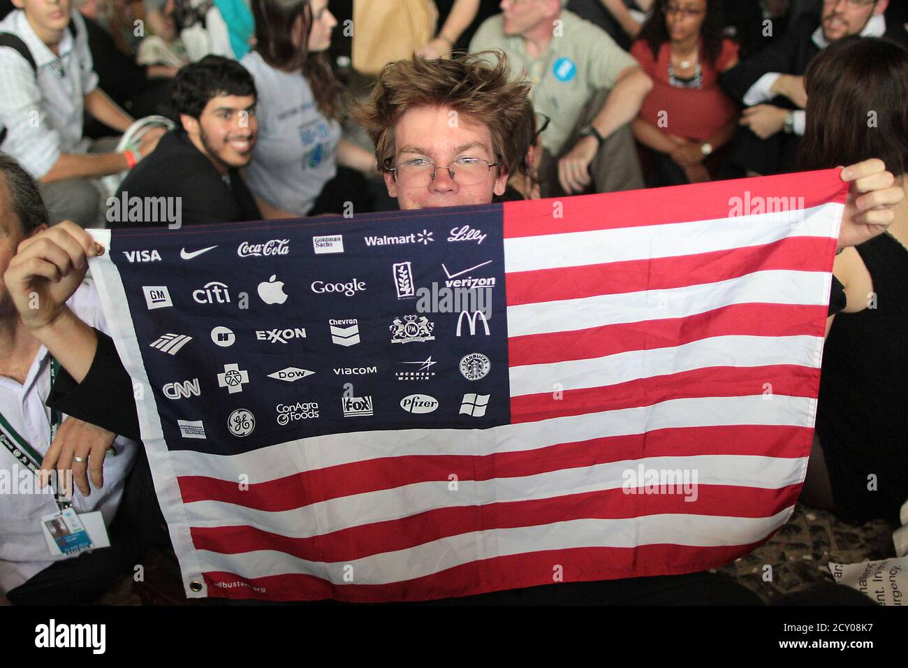 Youth Display The American Flag With Symbols Of Multinational Brands To Protest Against The Current Economic Policy During The Rio United Nations Conference On Sustainable Development In Rio De Janeiro June 21 Youth Display The American Flag With Symbols Of Multinational Brands To Protest Against The Current Economic Policy During The Rio United Nations Conference On Sustainable Development In Rio De Janeiro June 21
