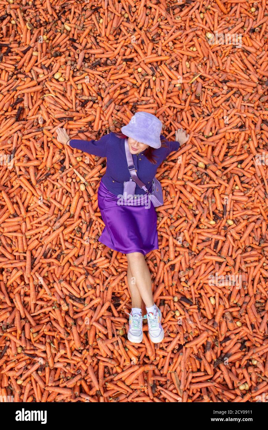 Student Lauren Gallagher with the art installation 'Grounding' by Rafael Perez Evans, which is made up of 29 tonnes of unwanted carrots ouside the Ben Pimlott building at Goldsmiths College, London. Stock Photo