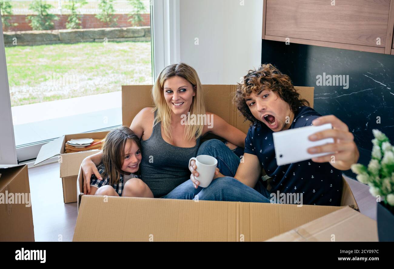 Family making selfie sitting inside moving box Stock Photo