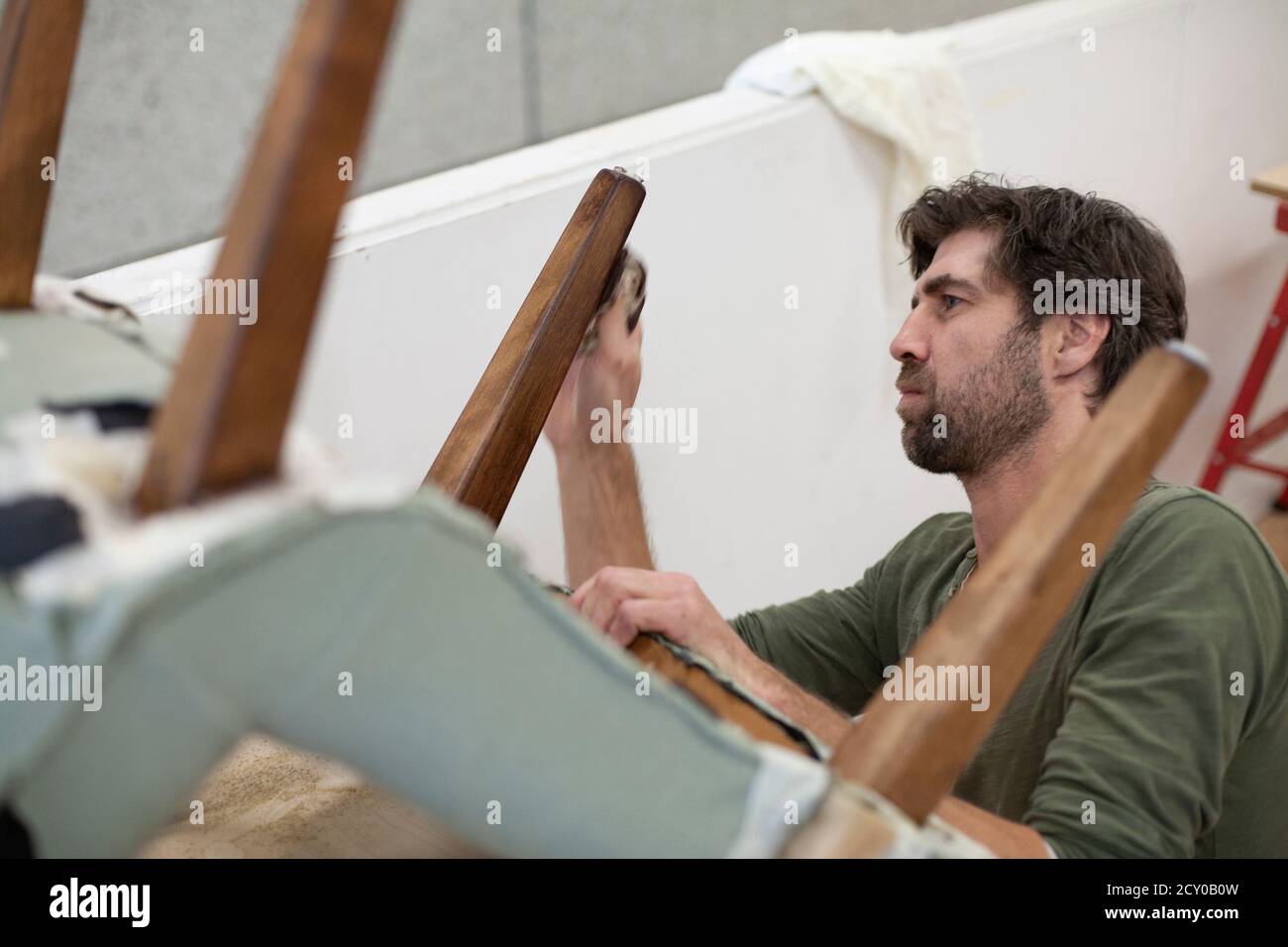 A focused craftsman polishes the leg of an antique chair Stock Photo