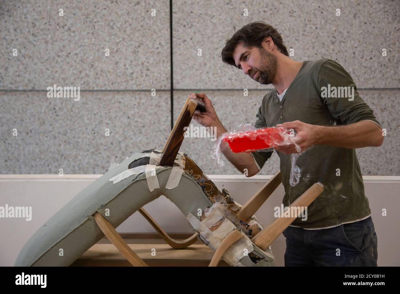 A man focused intently as he paints the legs of an antique chair Stock Photo