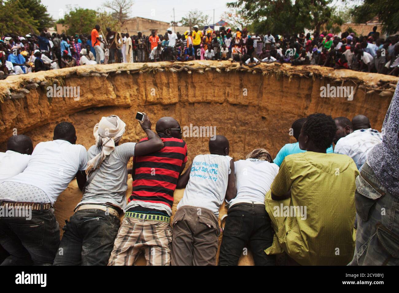 People watch a traditional ceremony taking place in a large former well in  the village of Ndande, Senegal, May 19, 2013. Every year, inhabitants of  the village take part in a Sufi