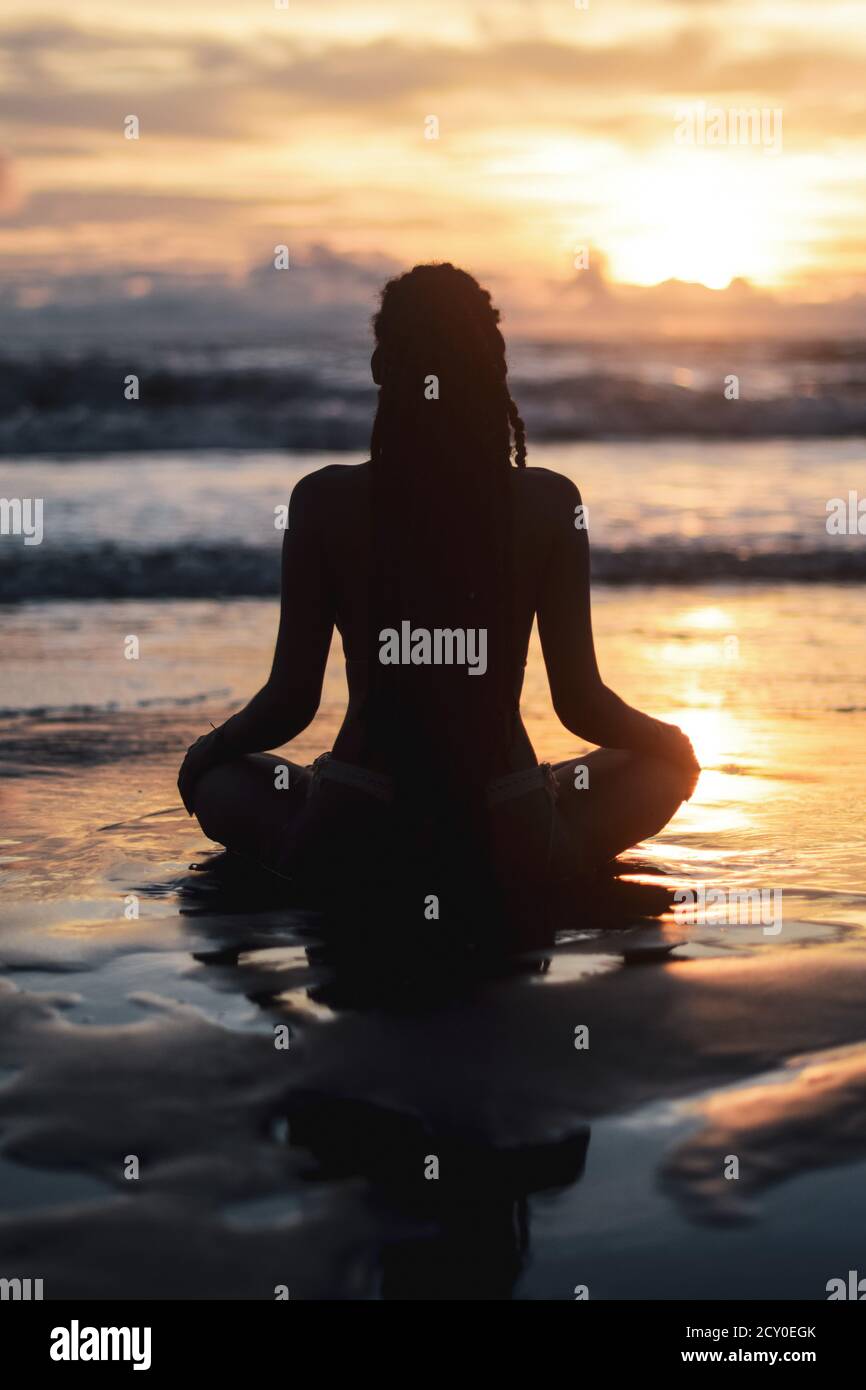 Silhouette of woman meditating on the beach at sunset Stock Photo - Alamy