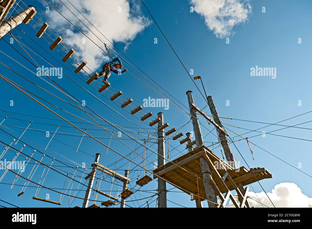 boy is balancing over a bridge at high rope access course in Iceland Stock Photo