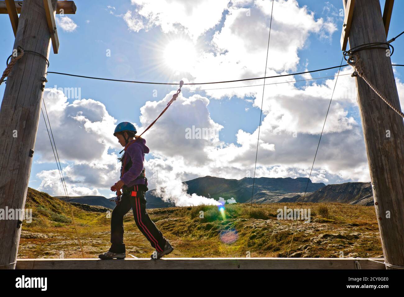 girl is balancing over a plank at high rope access course in Iceland Stock Photo