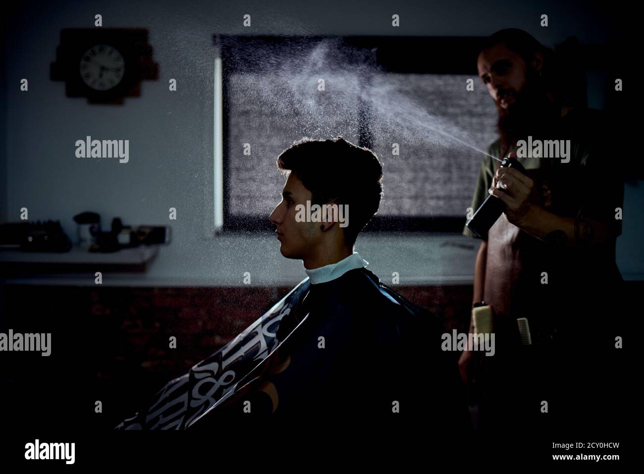 A barber spraying a customer's hair. concept Stock Photo Alamy