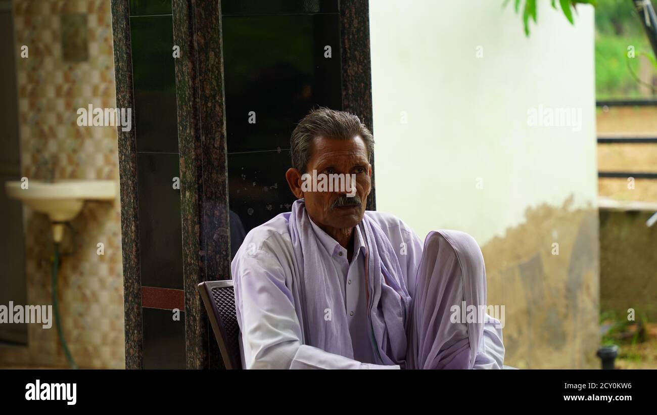 24 September 2020 : Reengus, Jaipur, India / Old Indian Rajasthani man sitting on a chair at home. Stock Photo