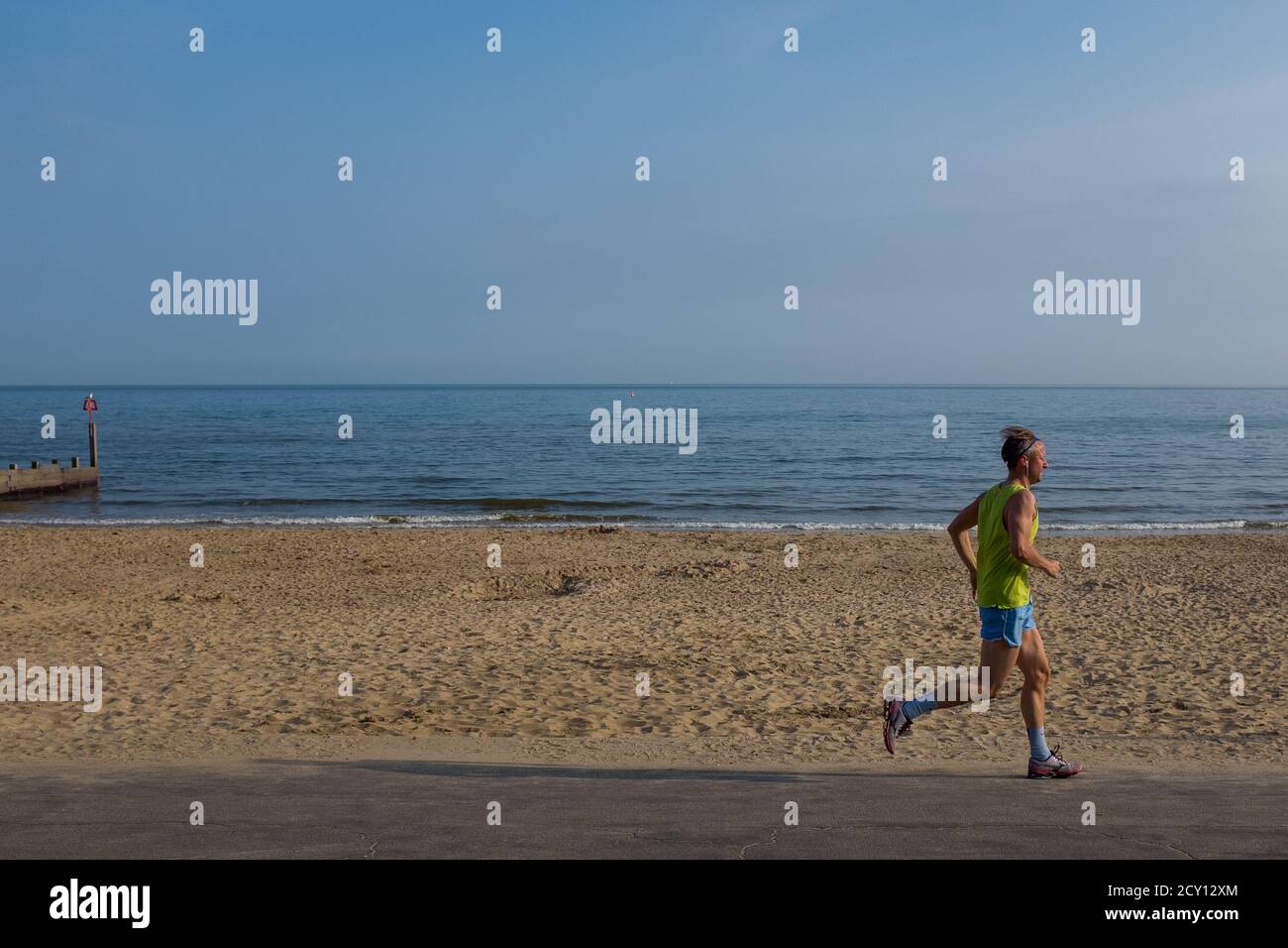 A solitary male jogger on the promenade on an early summer evening on the beach at Southbourne in Bournemouth. 06 June 2016. Photo: Neil Turner Stock Photo