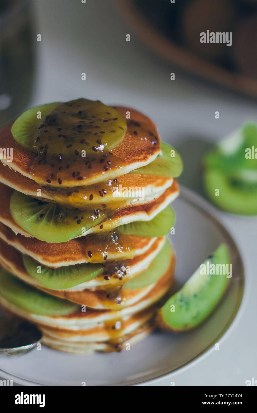 Plate of pancakes dripping with kiwi jam with kiwi pieces. Shrovetide Maslenitsa Butter Week festival meal. Shrove Tuesday. Pancake day Stock Photo