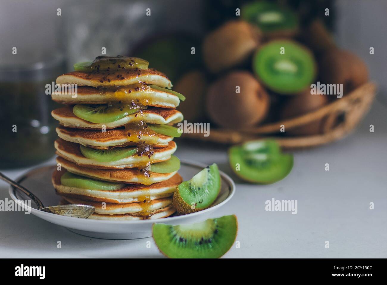 Plate of pancakes dripping with kiwi jam with kiwi pieces. Shrovetide Maslenitsa Butter Week festival meal. Shrove Tuesday. Pancake day Stock Photo