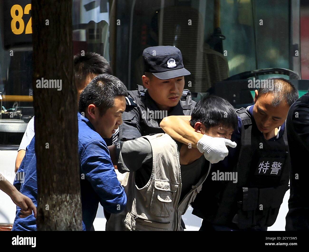 Policemen arrest a man (C), who held a woman hostage on a bus, on a street in Kunming, Yunnan province, China, May 14, 2015. Local police managed to rescue the hostage and arrest the man with the use of a stunt grenade after 90 minutes of negotiation. The reason of the crime is under investigation, local media reported. REUTERS/Wong Campion Stock Photo