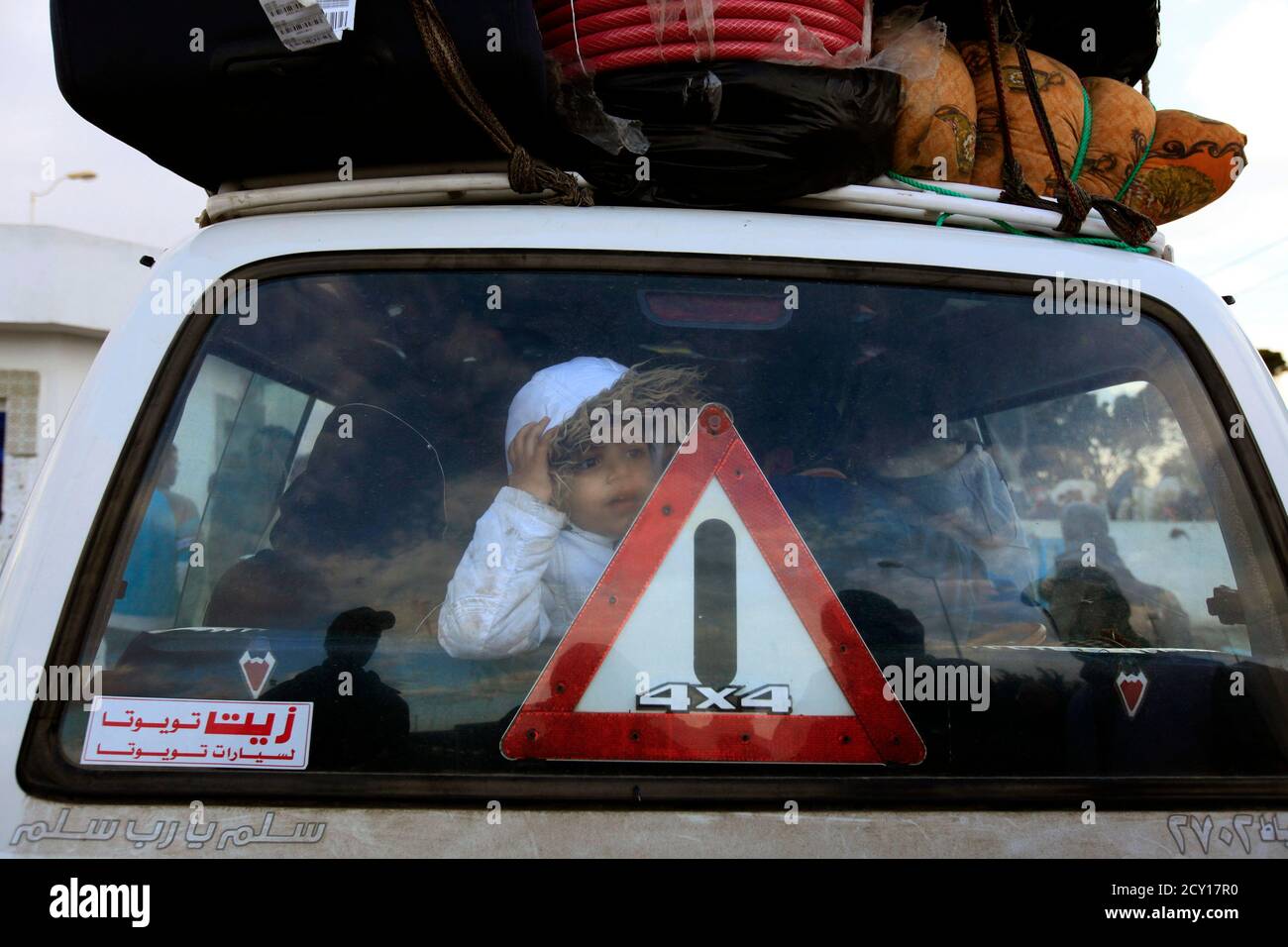 A Tunisian girl looks through the window of a van after she crosses the border into Tunisia at the border crossing of Ras Jdir after fleeing unrest in Libya February 23, 2011. Thousands of Tunisians are fleeing Libya, many across its western land border, after a bloody crackdown on protests against the rule of Muammar Gaddafi, state media reported on Tuesday. Tunisia has at least 30,000 nationals in Libya and officials fear they could become targets because of Tunisia's role in inspiring uprisings across the Arab world. Tunisia's leader was overthrown in January, and Egypt's president fell on  Stock Photo