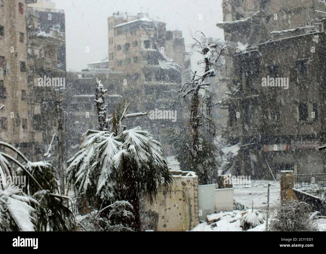 Snow falls over damaged buildings at Jouret al Shayah area in Homs January 9, 2013. REUTERS/Yazan Homsy       (SYRIA - Tags: CIVIL UNREST POLITICS ENVIRONMENT) Stock Photo