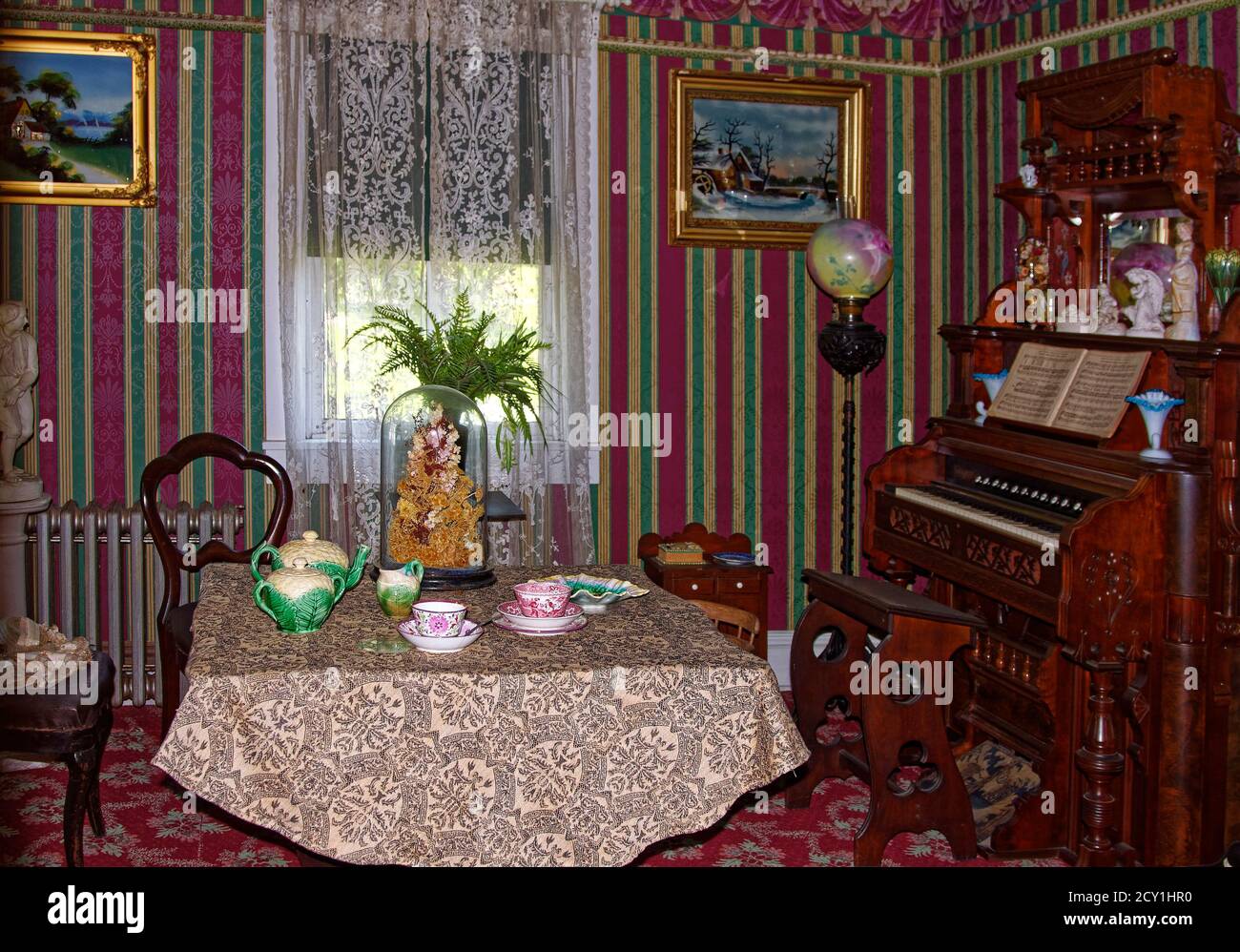 parlor, table, dishes, organ, carved wood, old, antiques, history, bold striped wallpaper, lace curtain, Landis Valley Village and Farm Museum, Pennsy Stock Photo