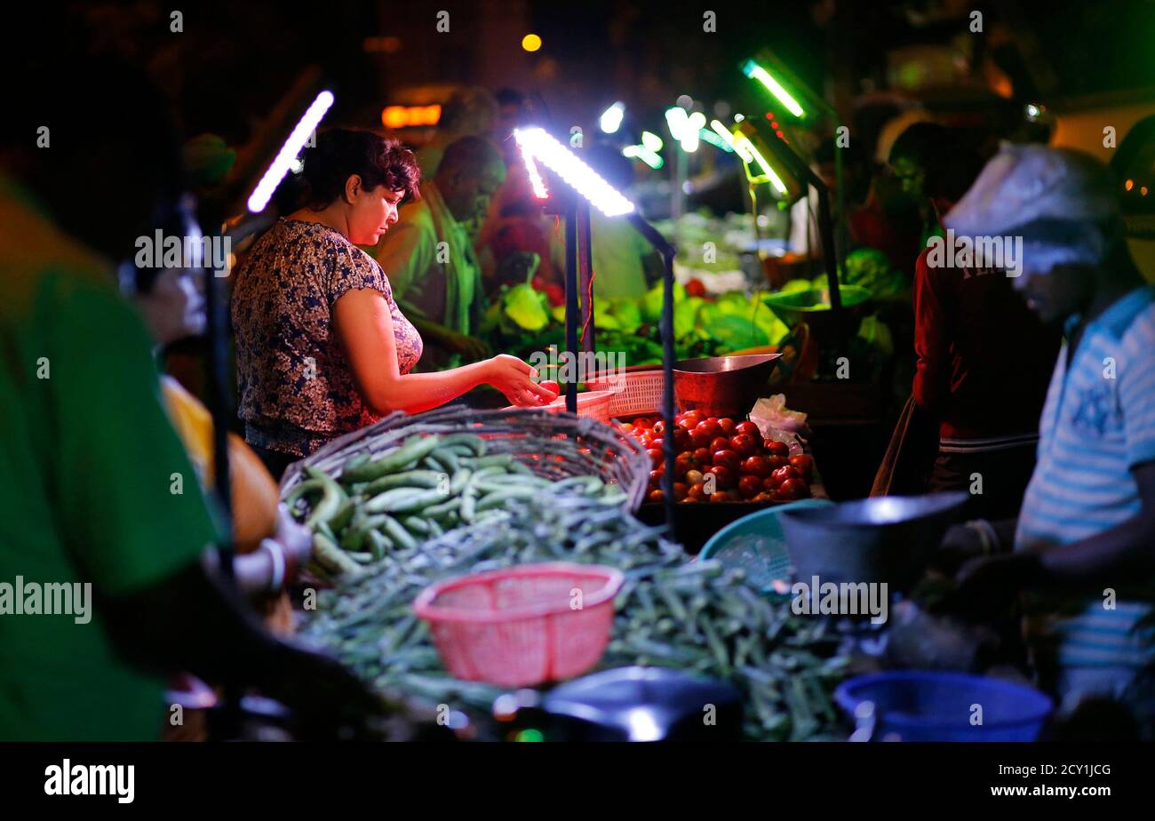 Customers shop at an open air evening vegetable and fruit market  illuminated by battery powered lights due to a power cut in New Delhi June  12, 2014. Swathes of north India are