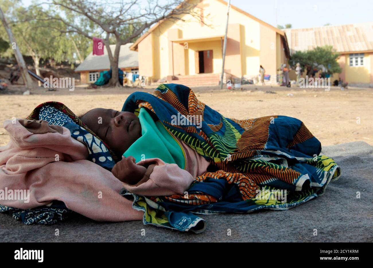 Baby Lurky, whose family was displaced as a result of Boko Haram attacks in the northeast region of Nigeria, sleeps in the shade at a camp for internally displaced people (IDP) in Yola, Adamawa State January 14, 2015. Boko Haram says it is building an Islamic state that will revive the glory days of northern Nigeria's medieval Muslim empires, but for those in its territory life is a litany of killings, kidnappings, hunger and economic collapse. Baby Lurky is one of over one hundred children born in the camps in Adamawa State since the community's displacement from their hometown in August 2014 Stock Photo