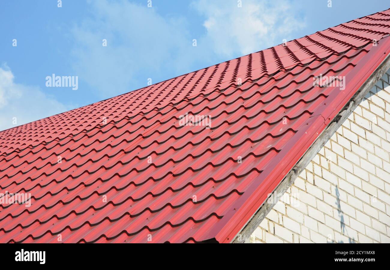 Building a new house with a metal red roof, roofing construction outdoors. Stock Photo