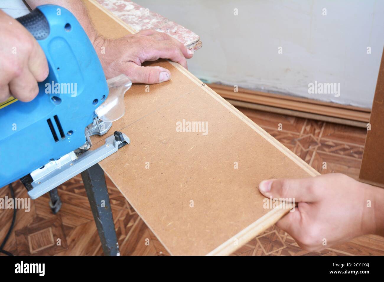 Contractor Cutting laminate flooring lengthwise. Workers Cutting laminate flooring with electric saw. Stock Photo