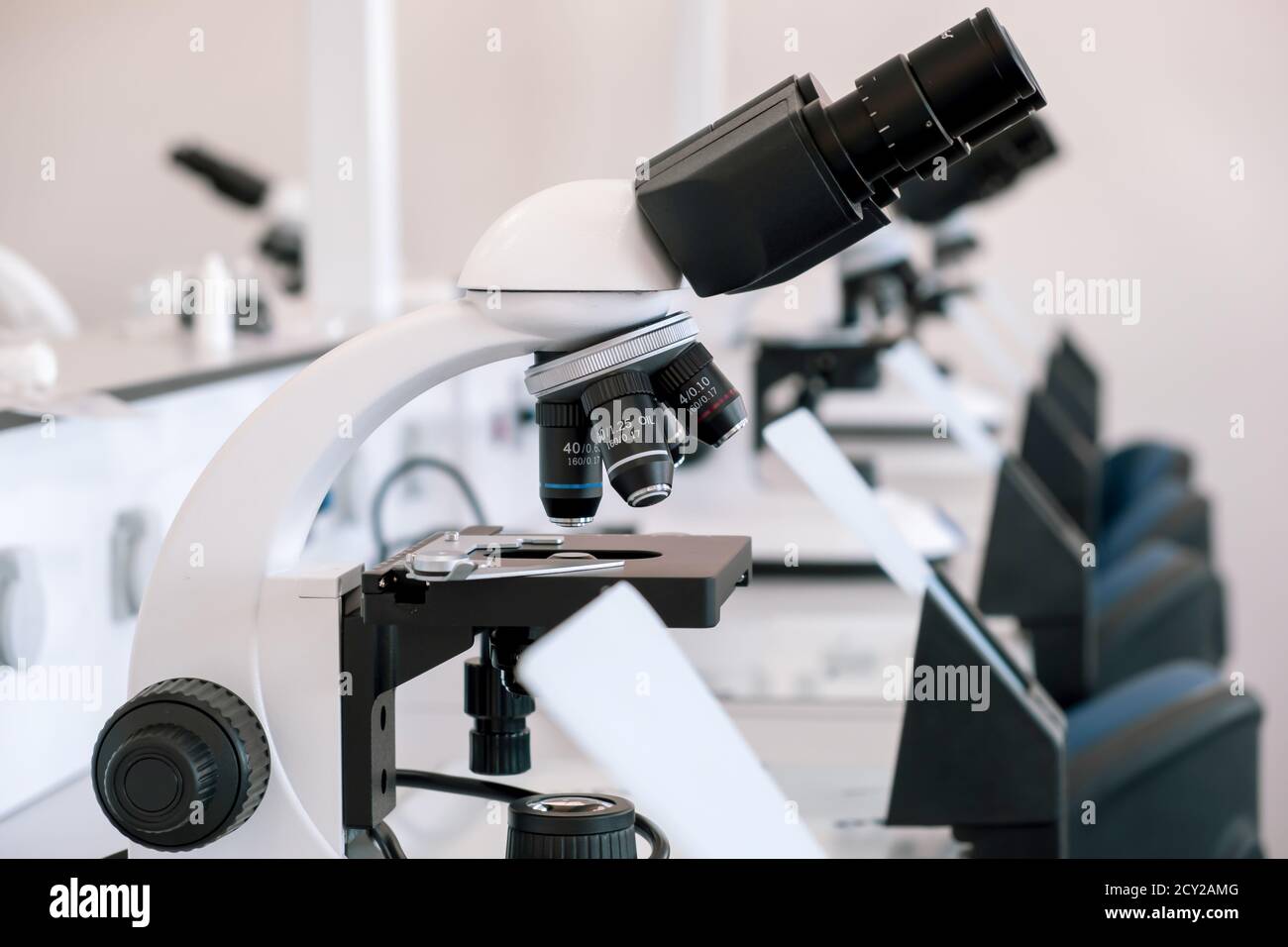 Microscope on table in the laboratory. Line of microscopes on tables in a hospital laboratory without people. Stock Photo