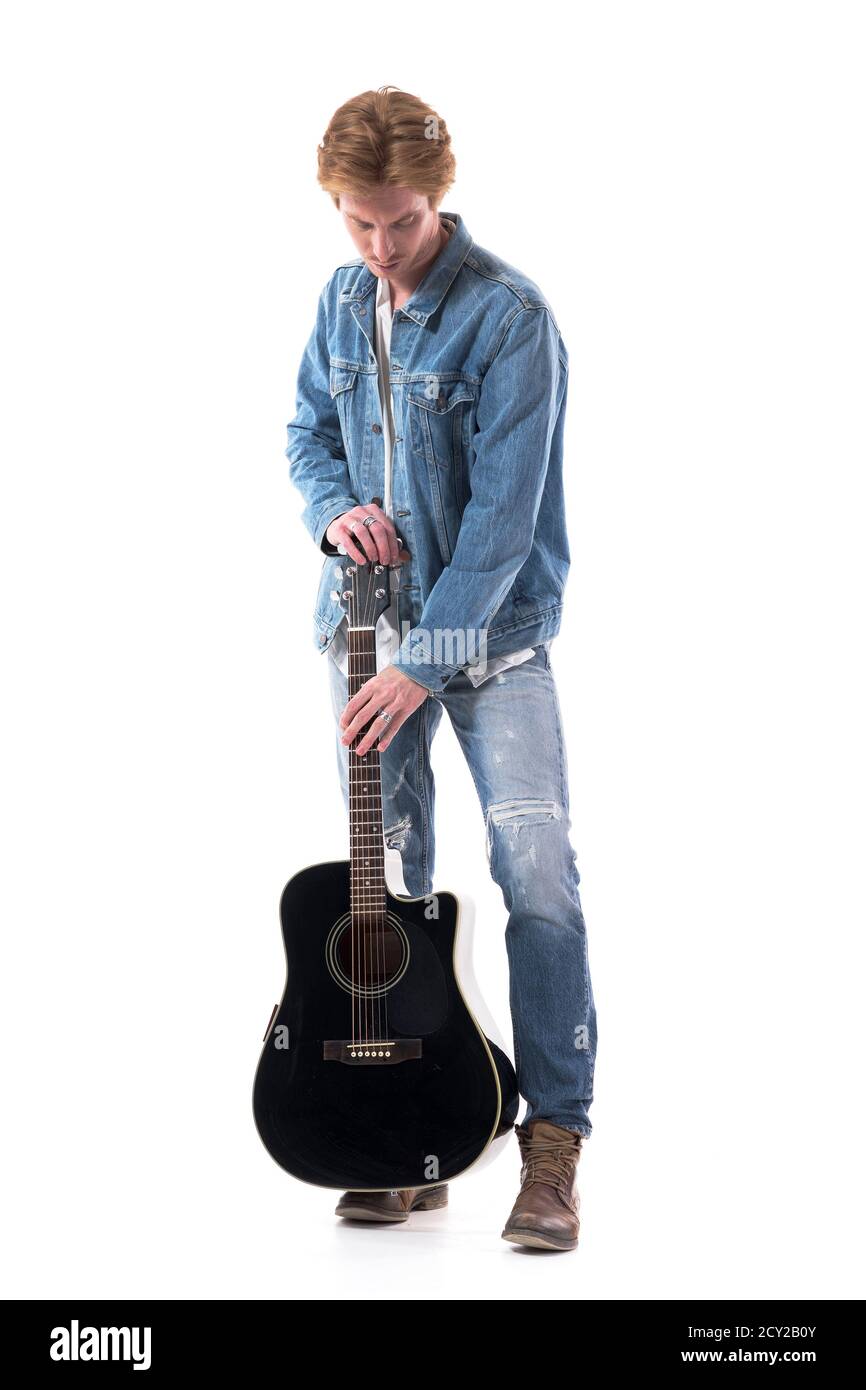 Rock music guitarist put away his acoustic guitar looking down. Full body isolated on white background. Stock Photo