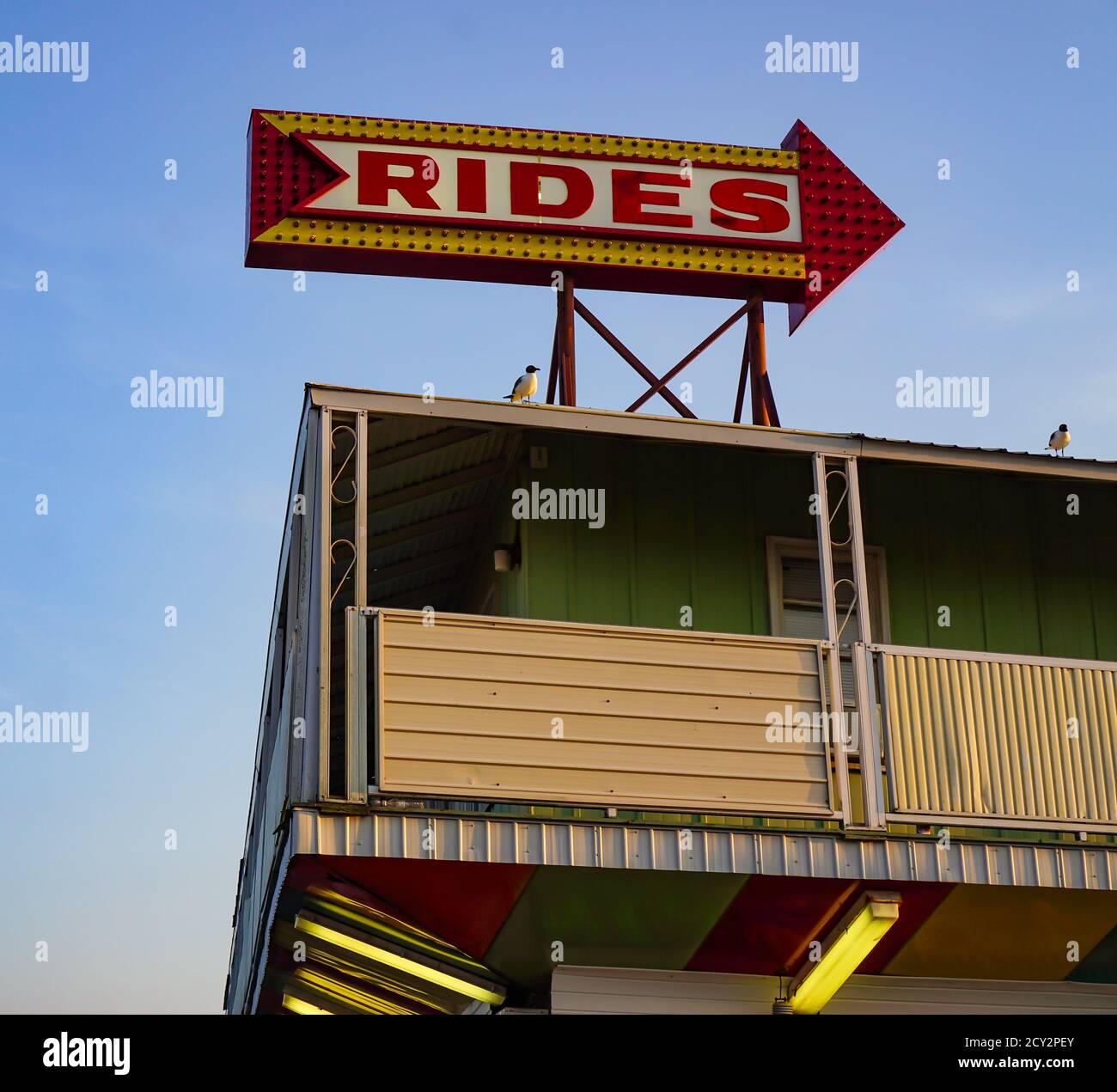 Corner of a building with an arrow shaped sign for amusement park rides ...