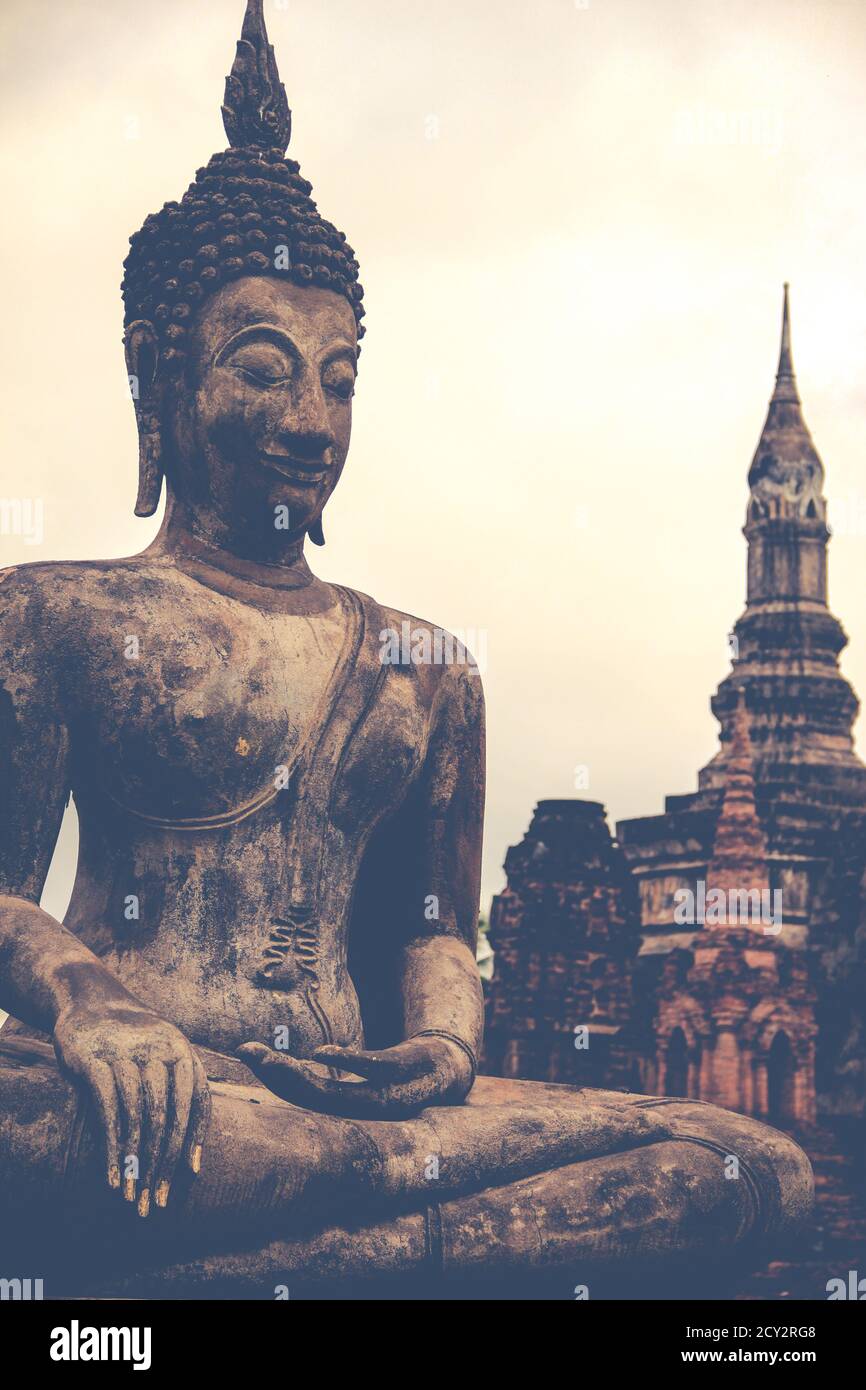 Sitting and weathered statue of Buddha at thailand with temple in the ...
