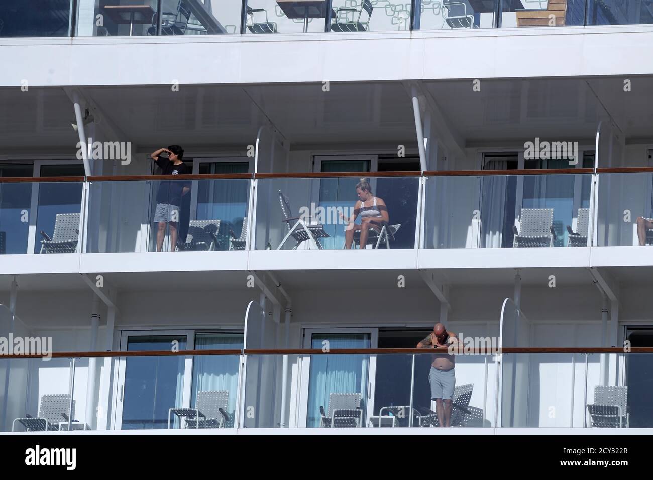 Passengers of the Mein Schiff 6 cruise ship stand outside their cabins as the ship is docked at Piraeus port