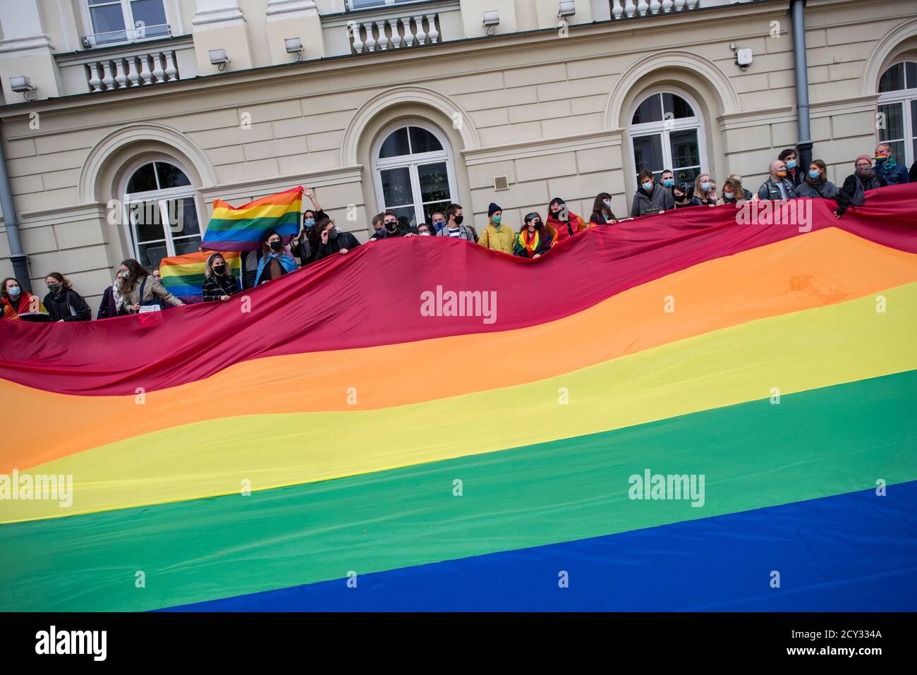 Activists hold a massive rainbow flag at the university campus during the protest.At the Warsaw University (UW, Uniwersytet Warszawski) students protested against the visit of the President Andrzej Duda on the occasion of the inauguration of the academic year. The Students' Antifascist Committee (Studencki Komitet Antyfaszystowski) who organized the protest claimed, that there is no place at the Warsaw University for Andrzej Duda, who during his election campaign openly dehumanized LGBTQ people, describing it as  an 'ideology'. The event took place in the time of growing hate speech against LG Stock Photo