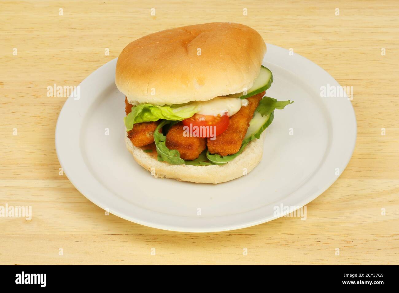 Fish fingers and salad in a roll on a plate on a wooden tabletop Stock Photo