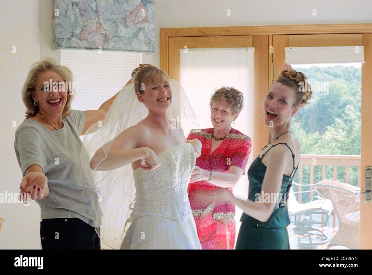 Mother and Bridal Attendants Assist Young Bride with her Wedding Gown