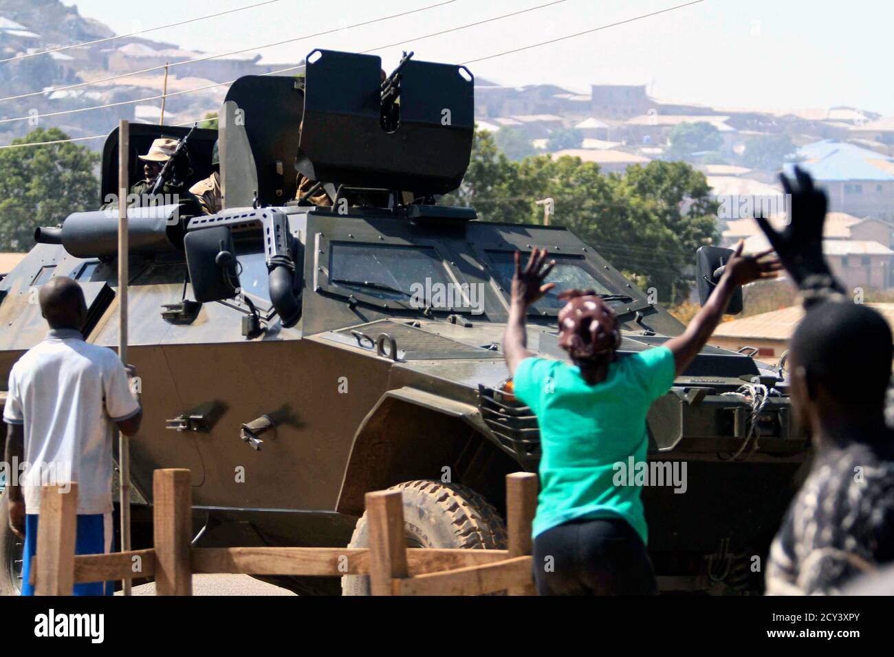 People wave as soldiers patrol the 