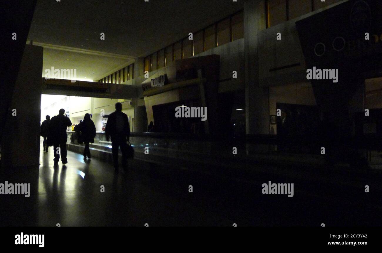 Passengers walk along a darkened corridor of Terminal C at Liberty International Airport after power outages occurred in Newark, February 7, 2011. Electrical equipment failures at a switching station in New Jersey caused the outage. REUTERS/Gary Hershorn (UNITED STATES - Tags: TRANSPORT BUSINESS) Stock Photo