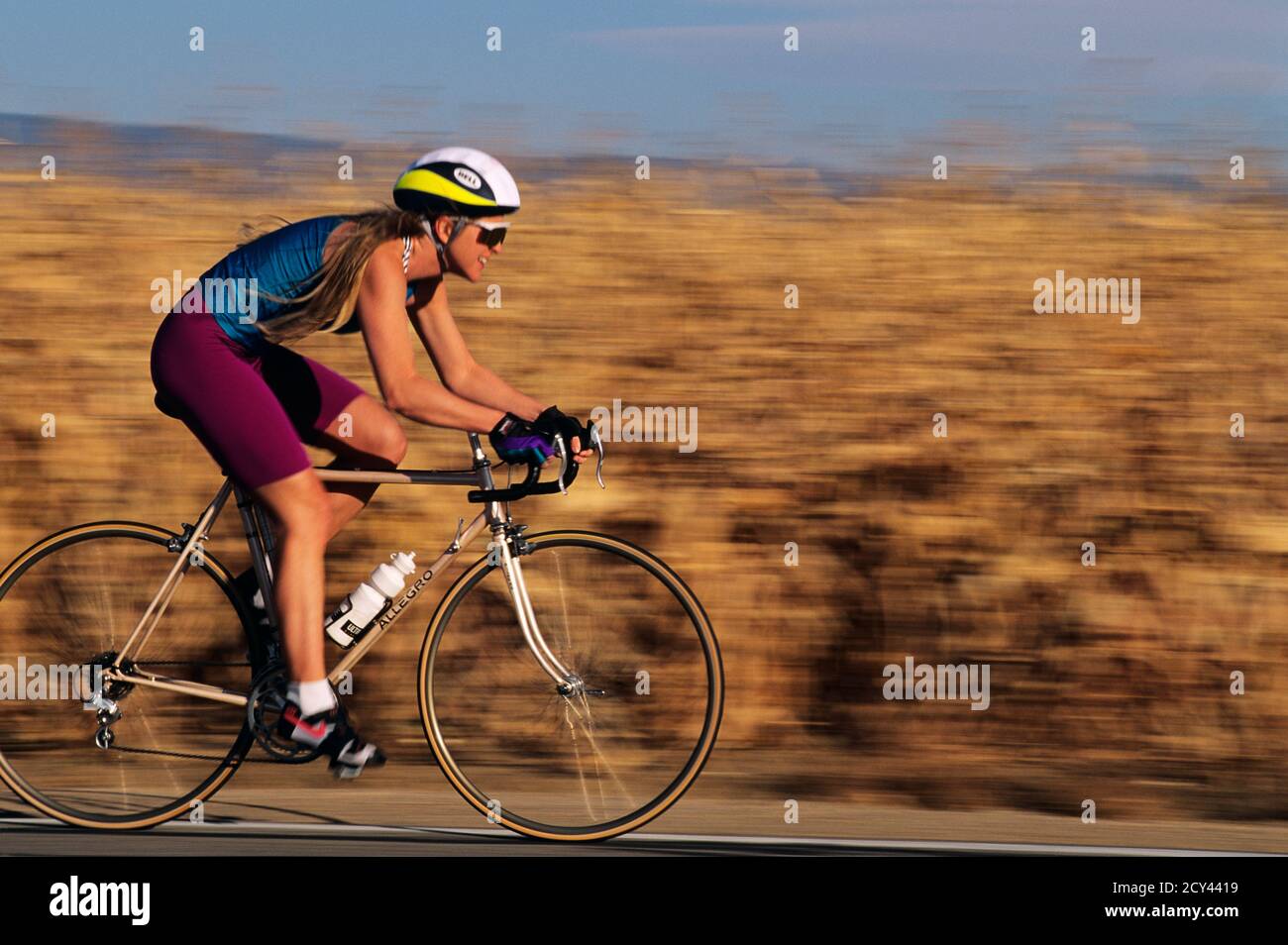 1990s ENERGETIC WOMAN RIDING BIKE ON RURAL HIGHWAY BACKGROUND