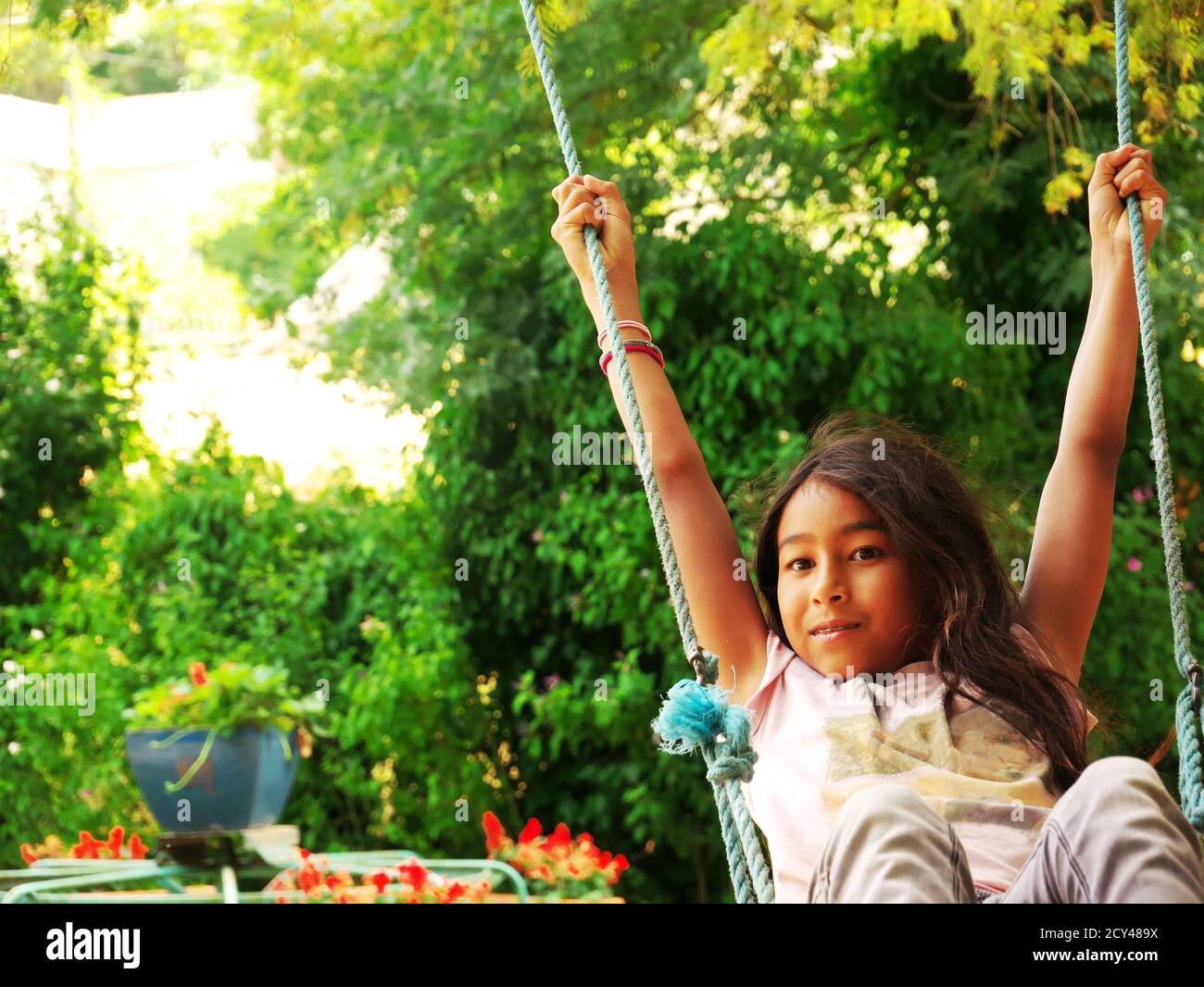 Young smiling mixed-race girl swinging in a park during the vacations Stock Photo