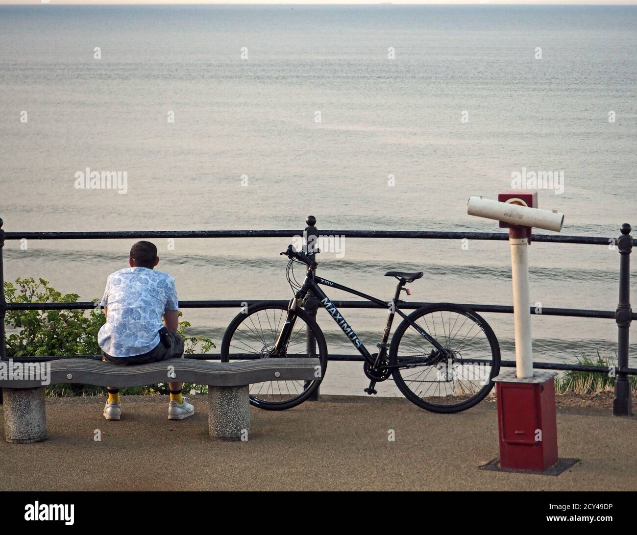 Cyclist resting and viewing sea while contemplating Covid 19 from Marine Parade, Saltburn Stock Photo