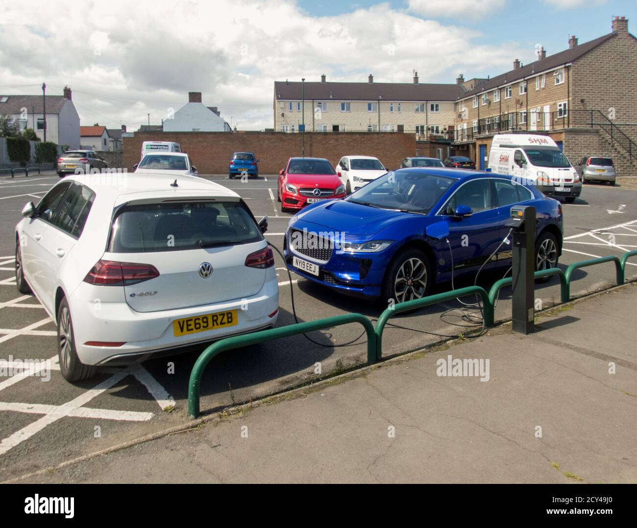 Electric Golf and Jaguar I-pace being charged in the public car park in Marske-by-the-Sea. Stock Photo