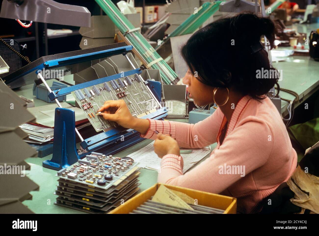 1970s SINGLE AFRICAN-AMERICAN WOMAN WORKER ASSEMBLING COMPUTER CIRCUIT BOARD IN FACTORY IN PENNSYLVANIA USA - ki4088 HAR001 HARS HEALTHINESS UNITED STATES HALF-LENGTH LADIES COMPUTERS PERSONS UNITED STATES OF AMERICA PROFESSION NORTH AMERICA NORTH AMERICAN SKILL OCCUPATION SKILLS WELLNESS HEAD AND SHOULDERS AFRICAN-AMERICANS AFRICAN-AMERICAN CAREERS PA ASSEMBLING BLACK ETHNICITY LABOR PRIDE IN EMPLOYMENT OCCUPATIONS HIGH TECH CONCEPTUAL EMPLOYEE CIRCUIT PRECISION YOUNG ADULT WOMAN COMPUTING HAR001 LABORING OLD FASHIONED AFRICAN AMERICANS Stock Photo